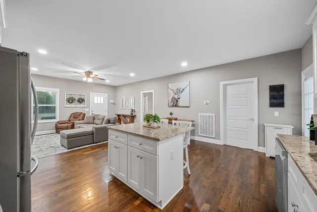 a kitchen with stainless steel appliances granite countertop white cabinets and a window