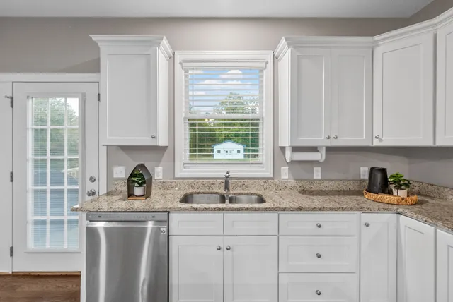 a living room with stainless steel appliances furniture and a wooden floor