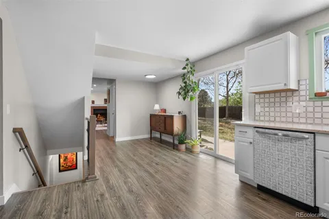 a open kitchen with granite countertop a stove top oven a sink dishwasher and a fireplace with wooden floor