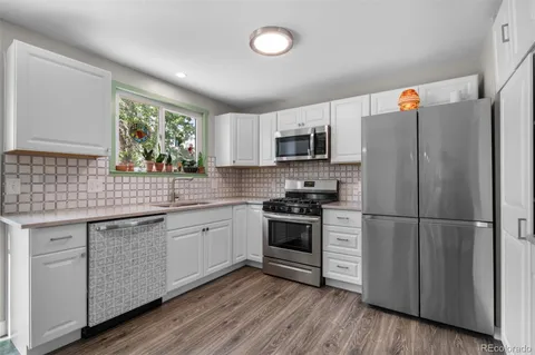 a kitchen with appliances a sink cabinets and a window