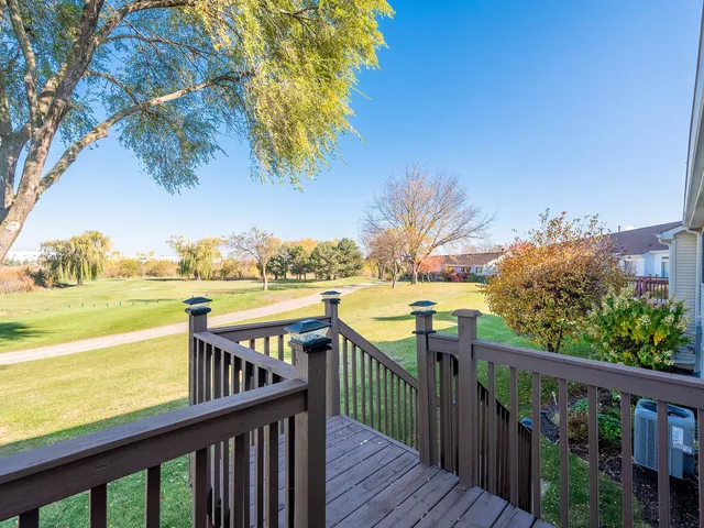 a view of a balcony with wooden chairs and floor to ceiling window
