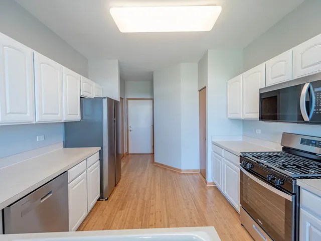 a kitchen with stainless steel appliances a stove a microwave and a hard wood floors