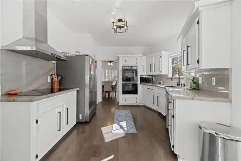 a kitchen with stainless steel appliances a refrigerator a stove a sink dishwasher and white cabinets next to a window