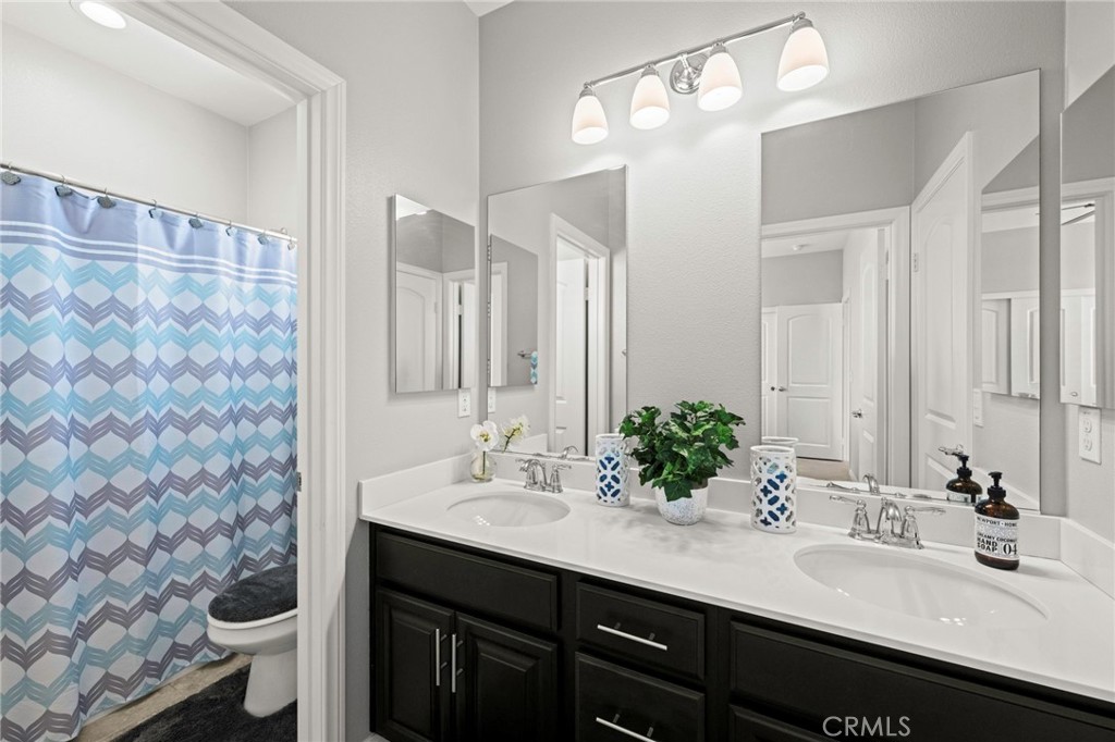 16555 Vía Los Caballeros Riverside, CA 92504 - Photo 29 of 51 a bathroom with a double vanity sink mirror and toilet