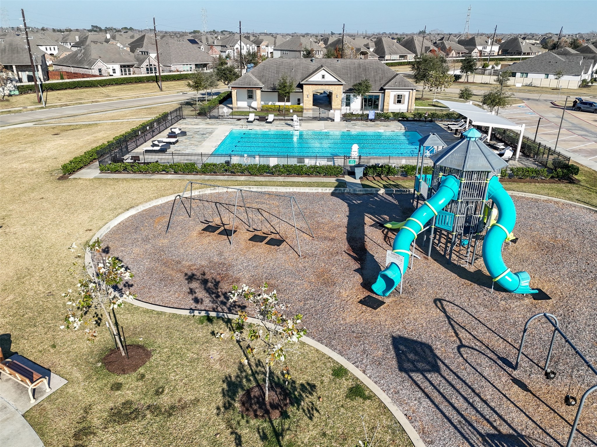4747 Abercorn Street Rosharon, TX 77583 - Photo 40 of 46 This community area features a swimming pool, playground with slides, and swings, providing ample recreational opportunities for families. It's surrounded by well-maintained landscaping and located in a neighborhood with nearby houses, offering a welcoming environment for residents.