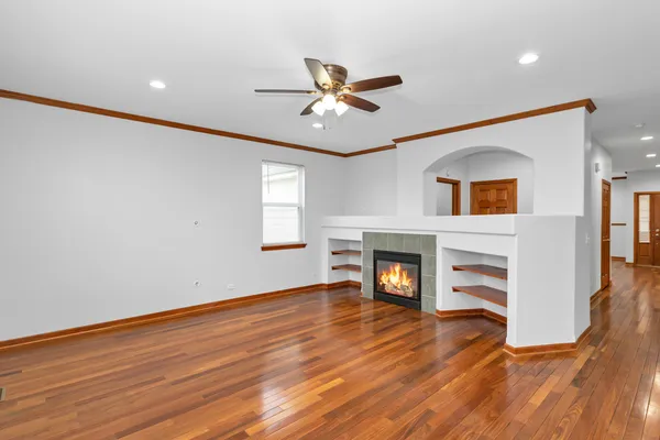 a view of a livingroom with a fireplace a ceiling fan and wooden floor