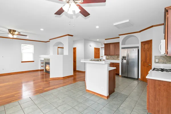 a kitchen with stainless steel appliances kitchen island granite countertop a refrigerator a stove top oven and white cabinets