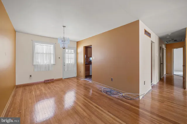 a view of an empty room with window and wooden floor