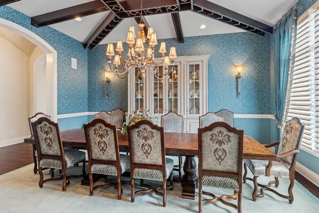 a dining room with wooden floor a chandelier a wooden table and chairs