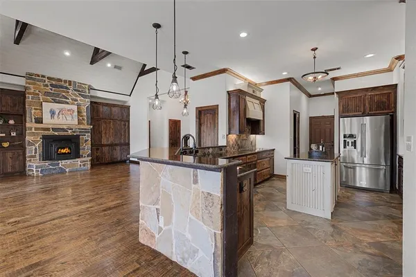 a kitchen with stainless steel appliances granite countertop a refrigerator a oven and a kitchen island with wooden floor