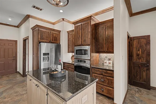 a kitchen with stainless steel appliances granite countertop a refrigerator a stove and a sink with wooden floor