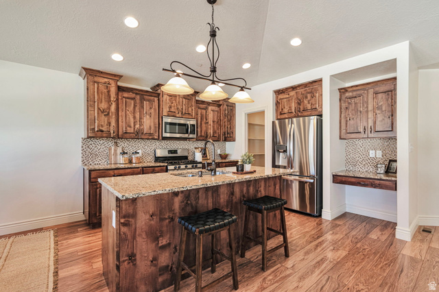 1288 North Horizon View Loop Elk Ridge, UT 84651 - Photo 8 of 40 Kitchen featuring tasteful backsplash, light wood-type flooring, stainless steel appliances, light stone countertops, and wood finish cabinets
