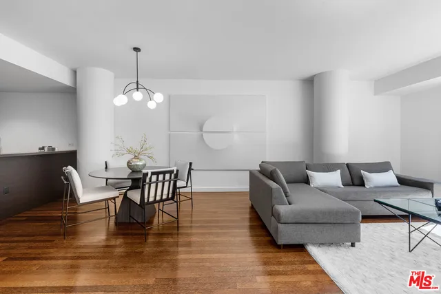 a living room with couches chairs and kitchen view with wooden floor