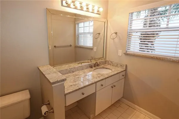 a bathroom with a granite countertop sink a toilet and a window