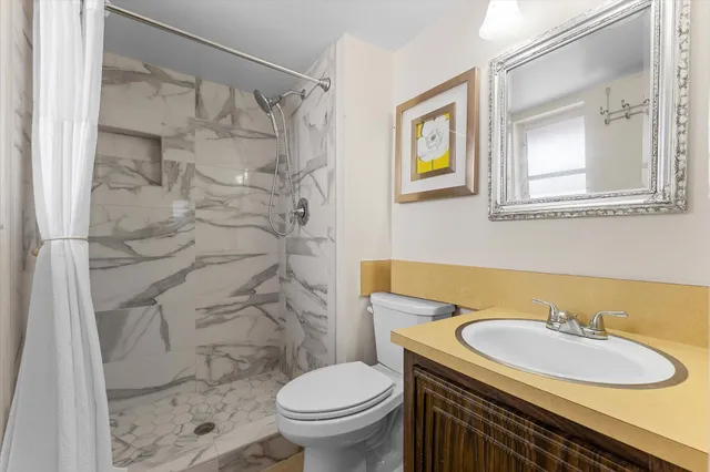 a bathroom with a sink toilet a mirror and shower