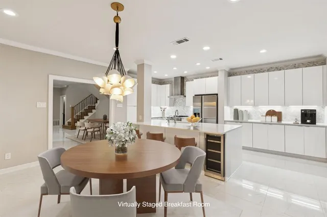 a kitchen with kitchen island a dining table chairs and white cabinets