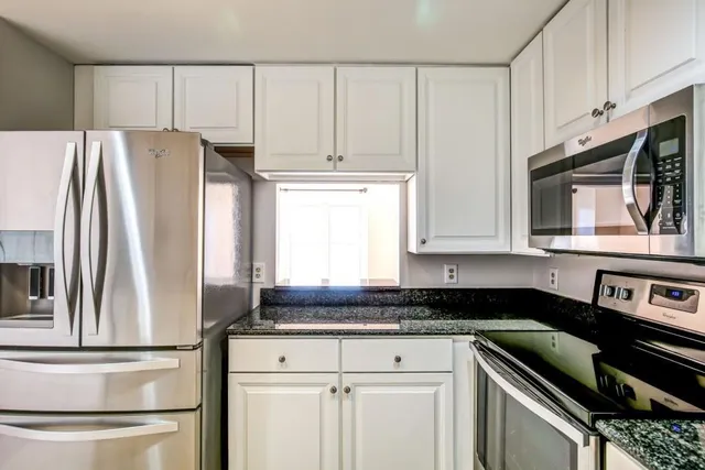 a kitchen with granite countertop white cabinets and stainless steel appliances
