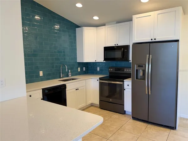 a kitchen with granite countertop a refrigerator and a stove top oven