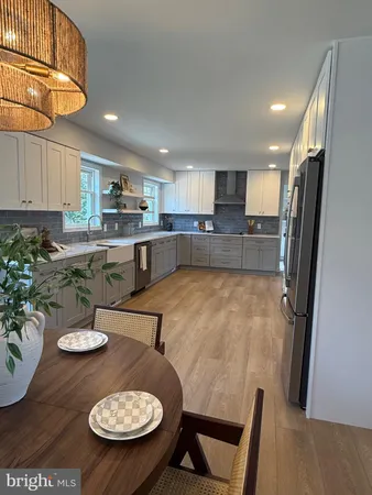 a kitchen with stainless steel appliances kitchen island granite countertop a refrigerator oven a sink dishwasher and white cabinets with wooden floor