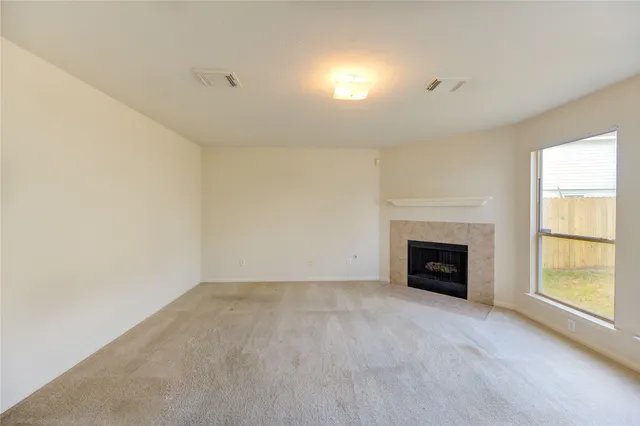 a view of an empty room with a window and a fireplace