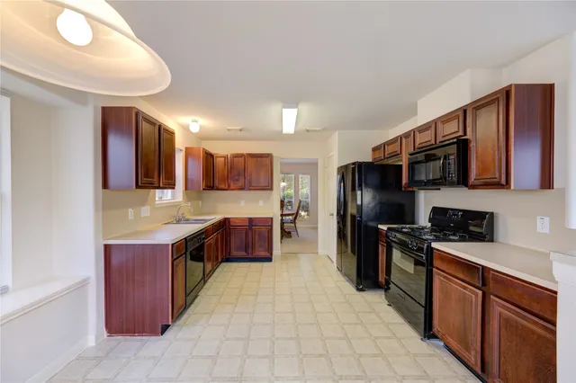 a large kitchen with stainless steel appliances granite countertop a stove refrigerator and a sink