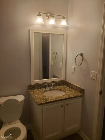 a bathroom with a granite countertop sink toilet and mirror