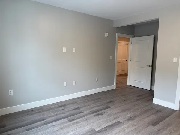 a view of an empty room with wooden floor and closet
