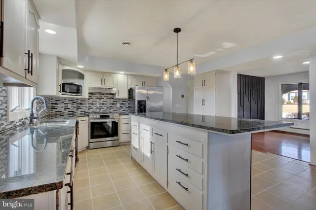 a kitchen with stainless steel appliances granite countertop a sink a stove top oven a counter space and cabinets