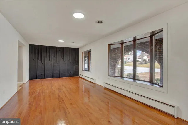 a view of an empty room with a window and wooden floor