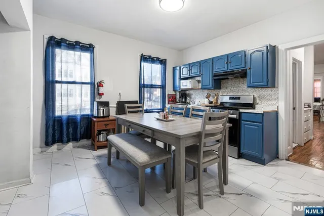 a kitchen with stainless steel appliances a sink a stove a refrigerator cabinets and dining table