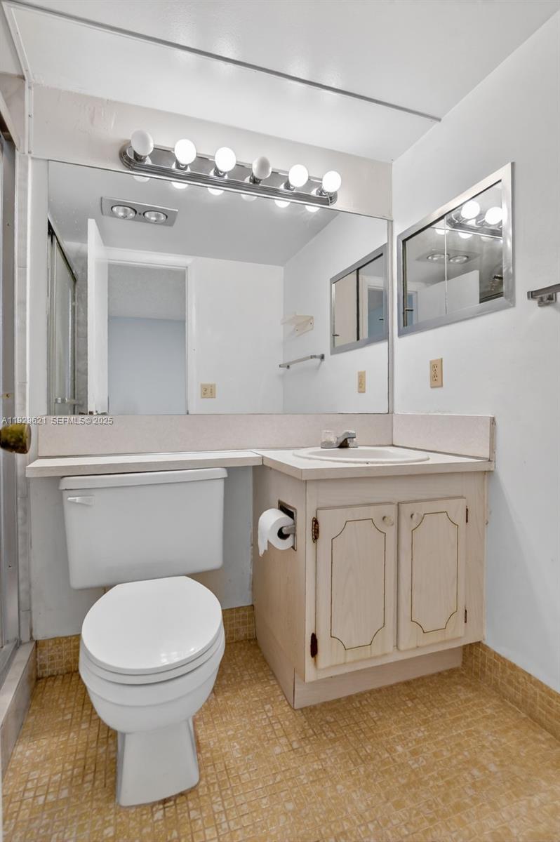 1008 Farnham North, Unit 1008 Deerfield Beach, FL 33442 - Photo 24 of 32 a bathroom with a toilet a sink a mirror and vanity