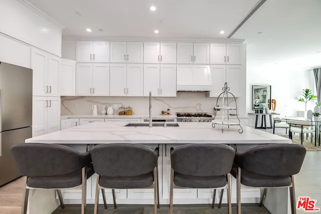 a kitchen with stainless steel appliances granite countertop a sink a stove a refrigerator and white cabinets with wooden floor