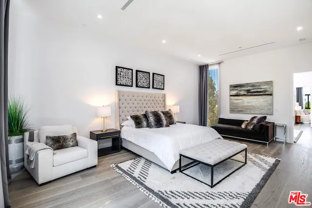 a spacious bedroom with a bed a couch and a potted plant