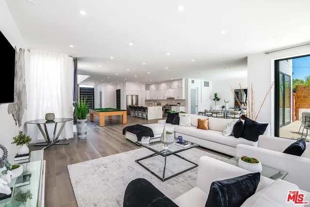 a living room with furniture kitchen view and a large window