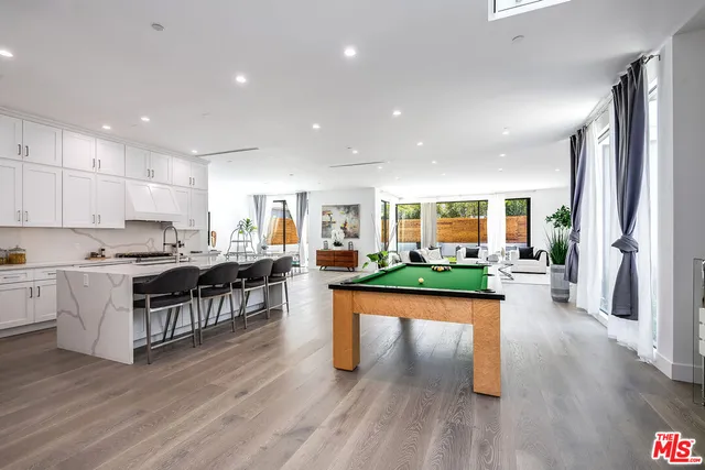 a living room with stainless steel appliances granite countertop lots of furniture and a wooden floor