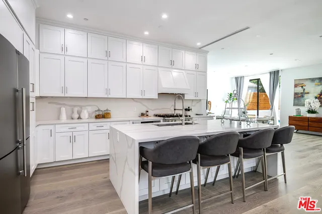 a kitchen with stainless steel appliances granite countertop a table chairs sink refrigerator and cabinets