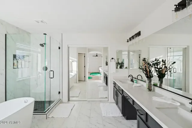 a spacious bathroom with a double vanity sink a mirror a bathtub and shower