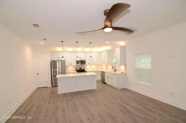 a large room with kitchen island a sink a stove and a refrigerator