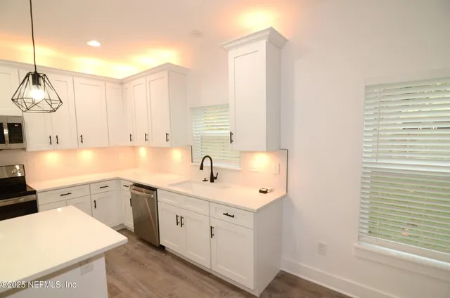 a kitchen with stainless steel appliances a refrigerator stove and white cabinets
