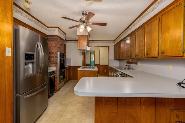 a kitchen with stainless steel appliances granite countertop a refrigerator a sink dishwasher a stove and a refrigerator