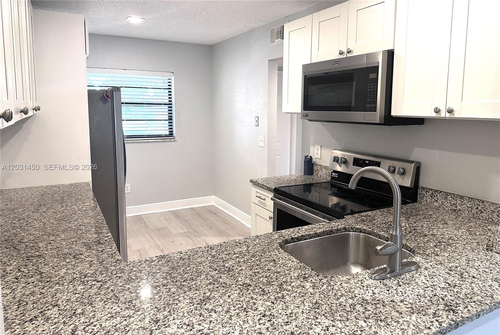 23398 Lyons Road, Unit 309 Boca Raton, FL 33428 - Photo 15 of 16 a kitchen with a sink a stove and microwave