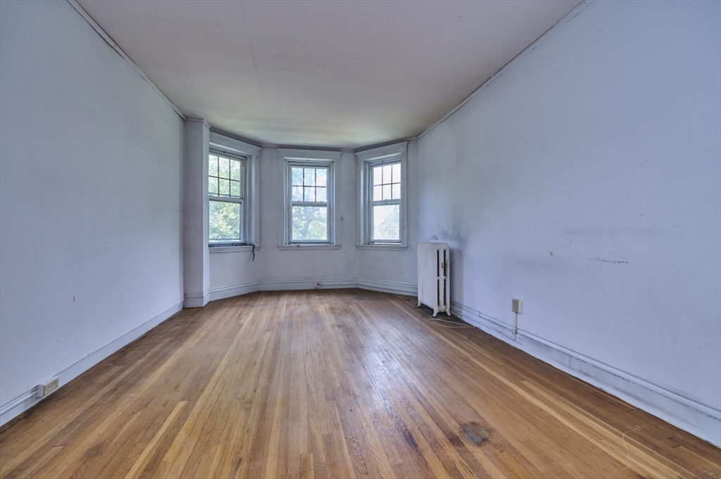 386 Riverway, Unit 4 Boston, MA 02115 - Photo 4 of 14 an empty room with wooden floor and windows