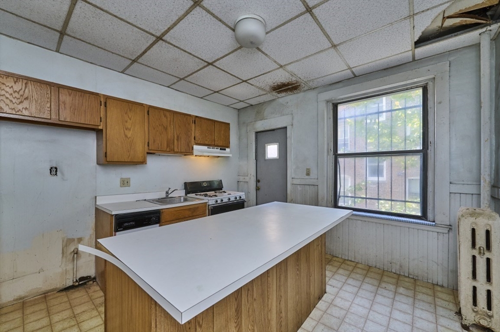 386 Riverway, Unit 4 Boston, MA 02115 - Photo 6 of 14 a kitchen with a stove a sink a refrigerator wooden floor and a window