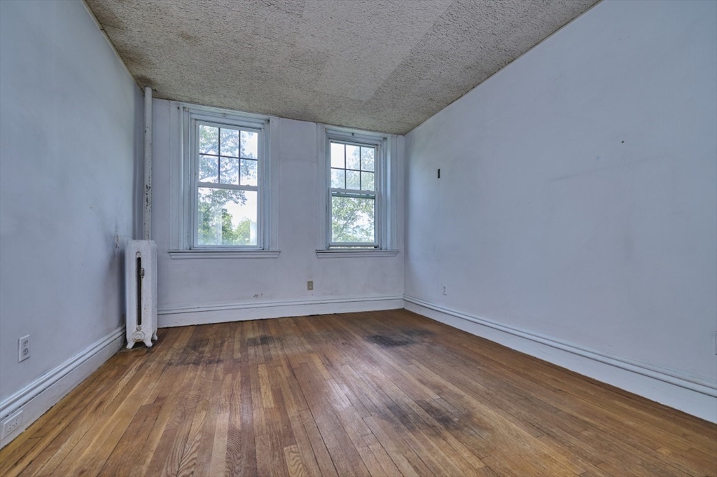 386 Riverway, Unit 4 Boston, MA 02115 - Photo 10 of 14 an empty room with wooden floor and windows