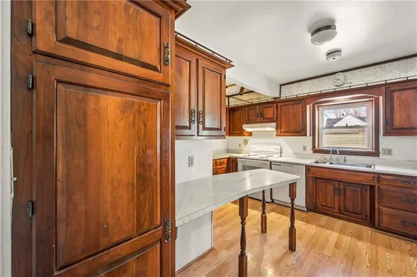 a kitchen with stainless steel appliances granite countertop wooden cabinets a dining table and chairs