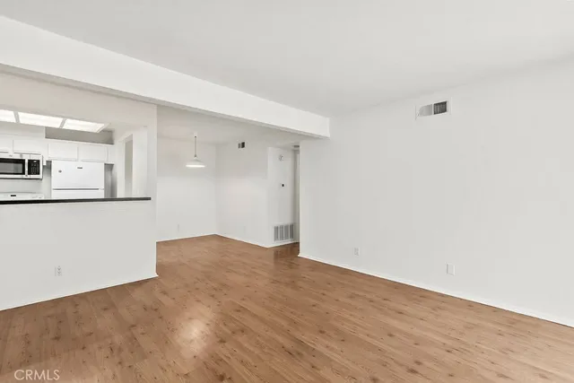 an empty room with wooden floor fireplace and windows