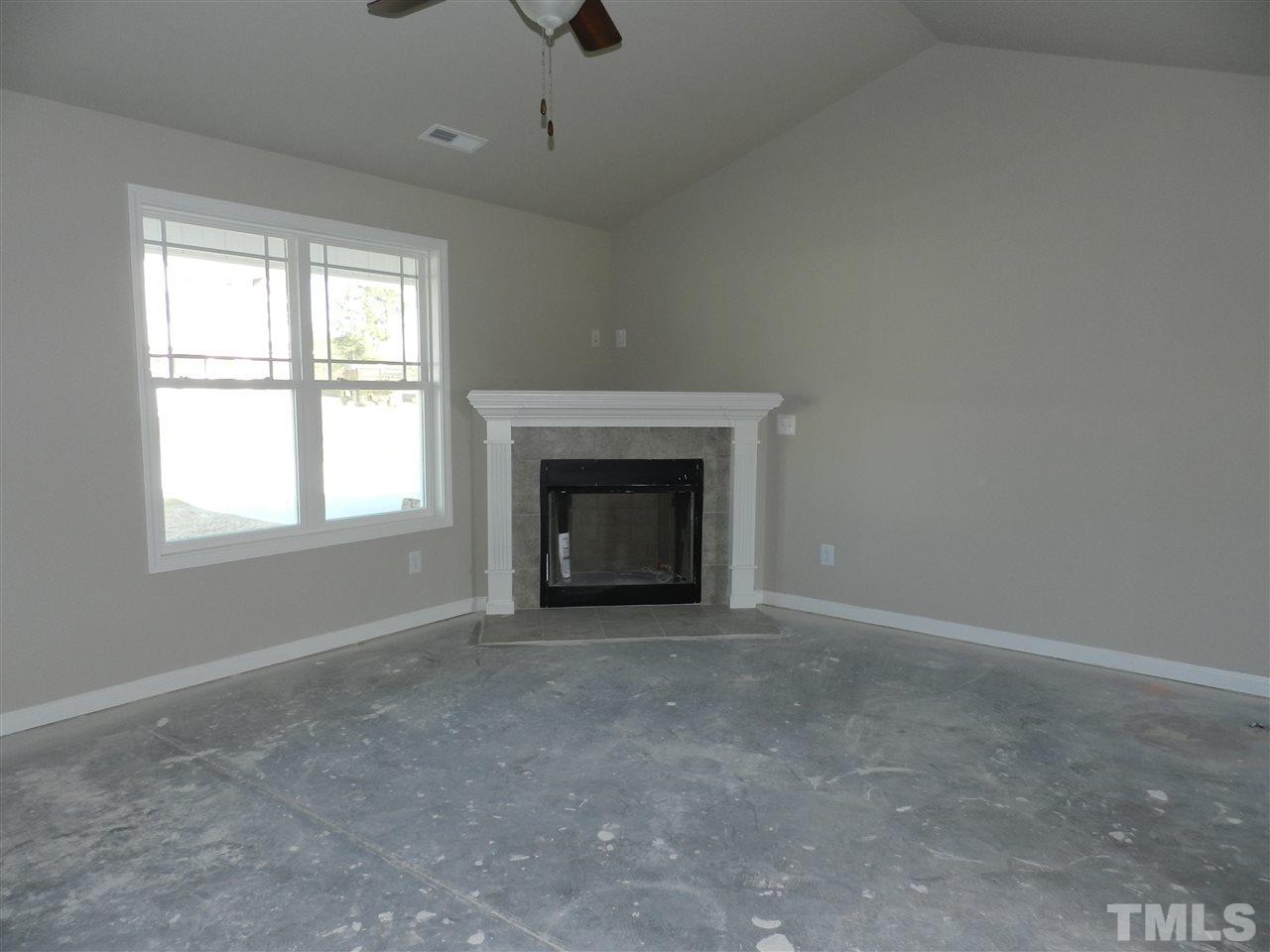 69 Willow Ridge Circle Willow Spring, NC 27592 - Photo 2 of 8 an empty room with a fireplace and windows
