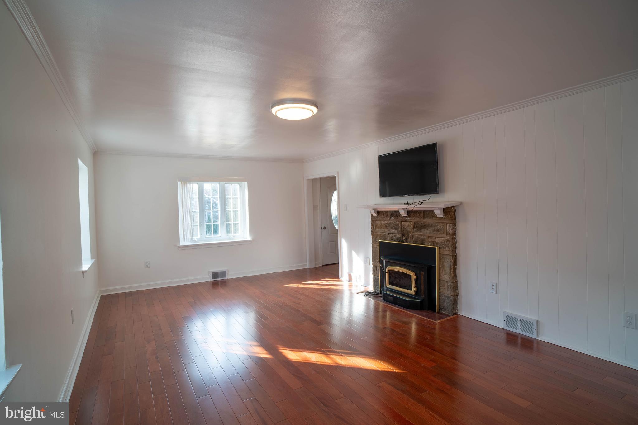 11 Wharton Lane Cheltenham, PA 19012 - Photo 7 of 17 an empty room with wooden floor fireplace and windows