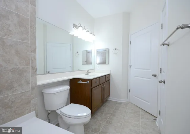 a bathroom with a granite countertop toilet sink and mirror