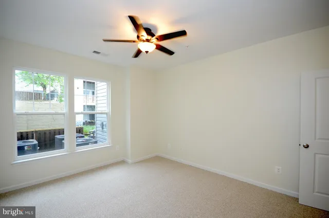 an empty room with windows and fan